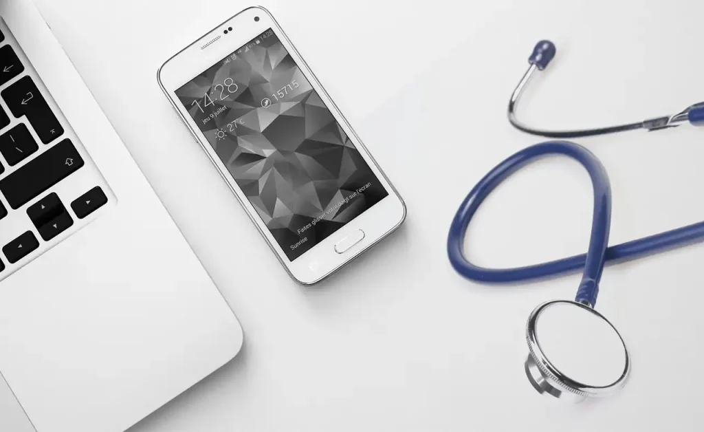 ノートパソコン、スマートフォン、聴診器が並んだ医療用デスク